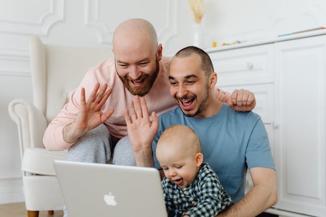 A diverse couple and child smiling at a laptop, representing Tech To Thrive personal coaching for family life, confidence, and digital literacy.